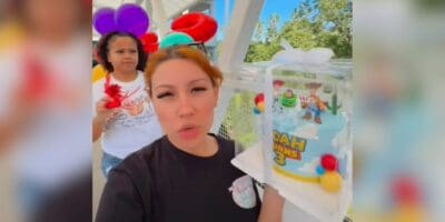 A baker holding the cake and balloons she brought to the Disneyland Hotel