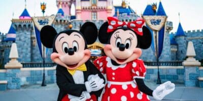 Mickey and Minnie Mouse pose in front of Sleeping Beauty Castle at Disneyland.