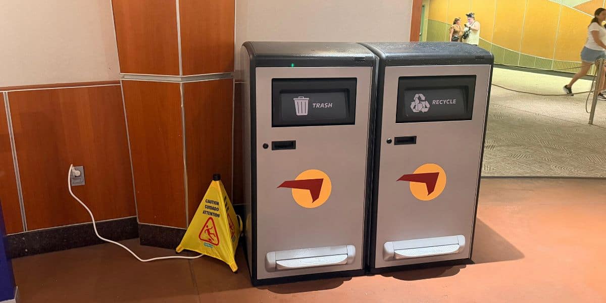 Trash and recycling bins next to a yellow wet floor sign at Walt Disney World.