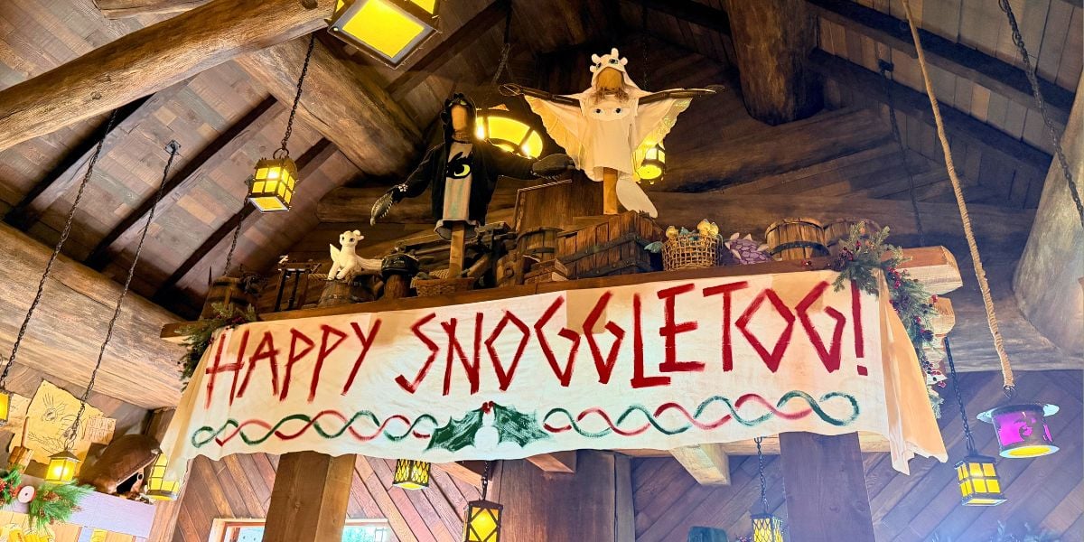 Toothless and Light Fury figures from DreamWorks Dragons above a “Happy Snoggletog!” holiday banner.