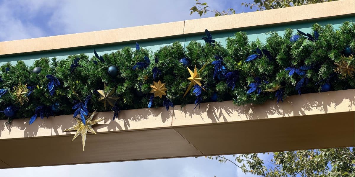 Festive evergreen garland adorned with blue ornaments and gold stars displayed on a holiday park archway.