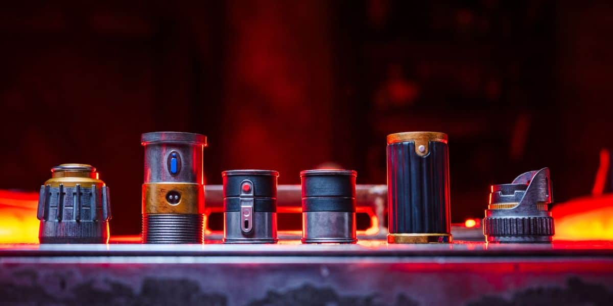 Six lightsaber hilt components laid out on a table at Savi’s Workshop in Star Wars: Galaxy’s Edge.