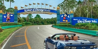 a blue car full of disney fans drives toward walt disney world entrance